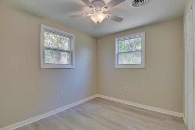 unfurnished room with a wealth of natural light, light wood-style flooring, visible vents, and baseboards