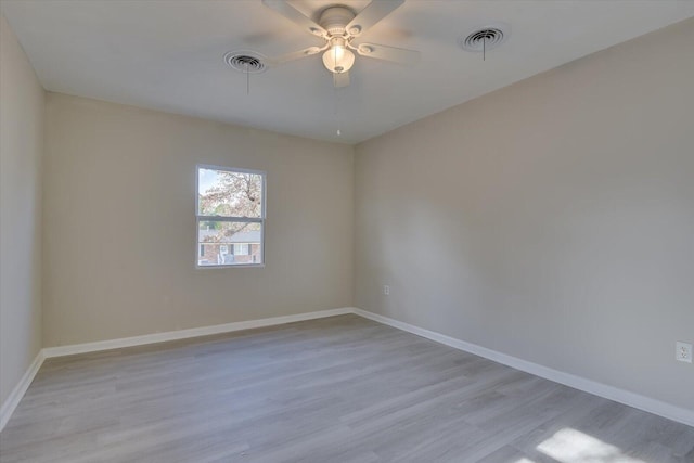 spare room with light wood-type flooring, visible vents, and baseboards