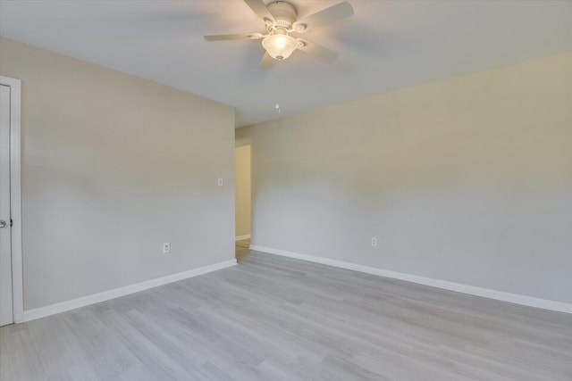 empty room with ceiling fan, light wood-style flooring, and baseboards