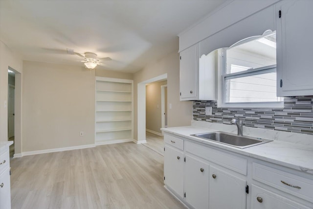 kitchen with ceiling fan, a sink, white cabinetry, light wood finished floors, and tasteful backsplash