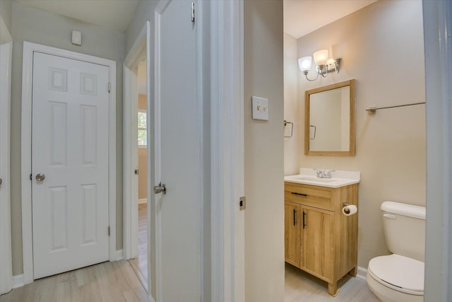 bathroom featuring wood finished floors, vanity, toilet, and baseboards