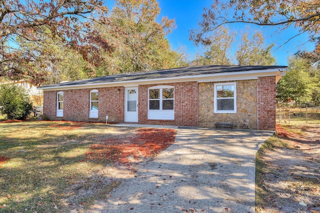 single story home featuring stone siding, brick siding, fence, and a front lawn