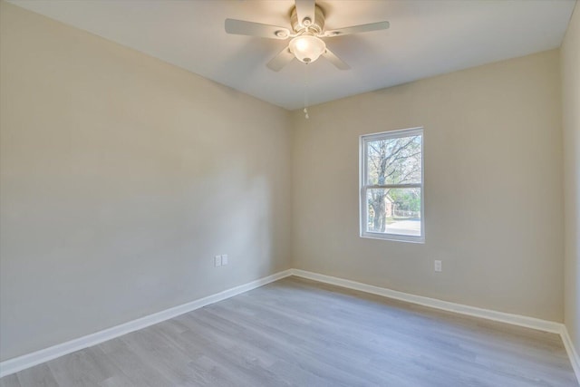 spare room featuring ceiling fan, light wood-style flooring, and baseboards