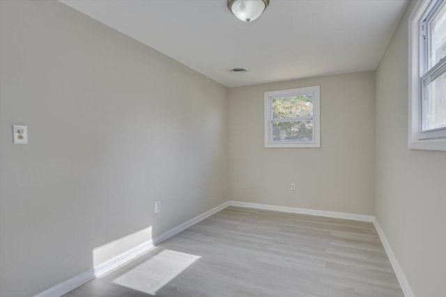 unfurnished room featuring light wood-style floors, visible vents, and baseboards