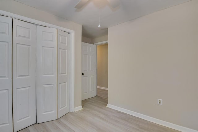 unfurnished bedroom featuring ceiling fan, a closet, light wood-style flooring, and baseboards