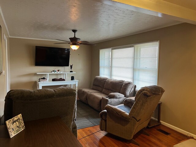 living room featuring a textured ceiling, ceiling fan, wood-type flooring, and crown molding