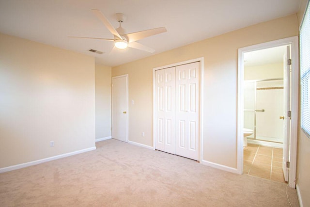 unfurnished bedroom featuring ensuite bathroom, light carpet, ceiling fan, and a closet