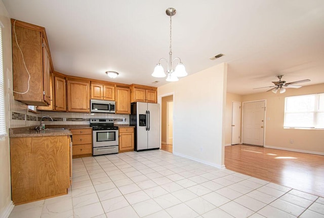 kitchen featuring pendant lighting, sink, appliances with stainless steel finishes, tasteful backsplash, and dark stone counters