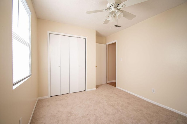 unfurnished bedroom with light colored carpet, ceiling fan, and a closet