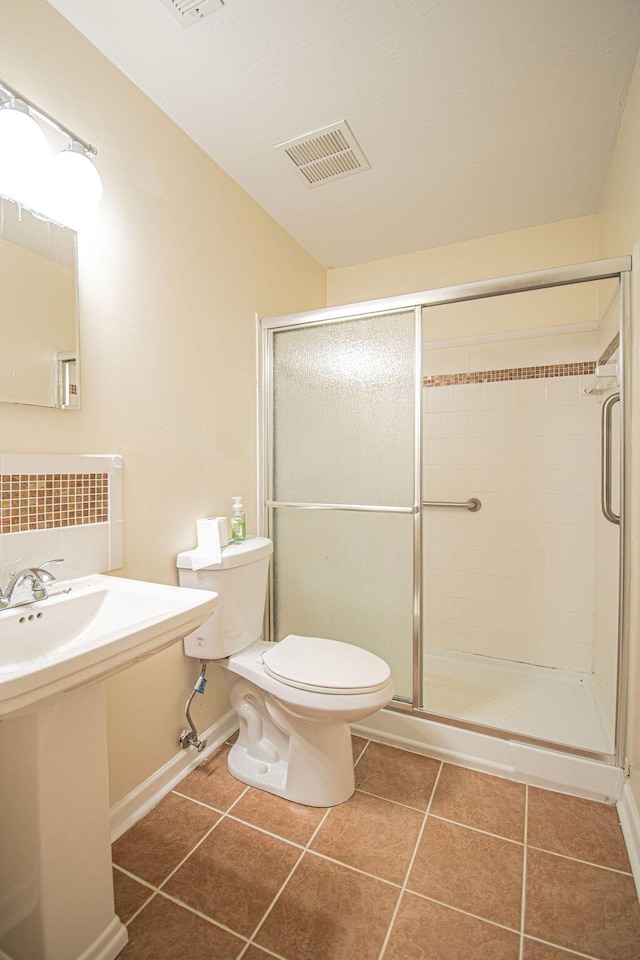 bathroom featuring walk in shower, sink, toilet, and tile patterned flooring