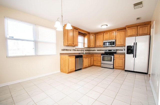 kitchen featuring decorative light fixtures, sink, backsplash, a notable chandelier, and stainless steel appliances