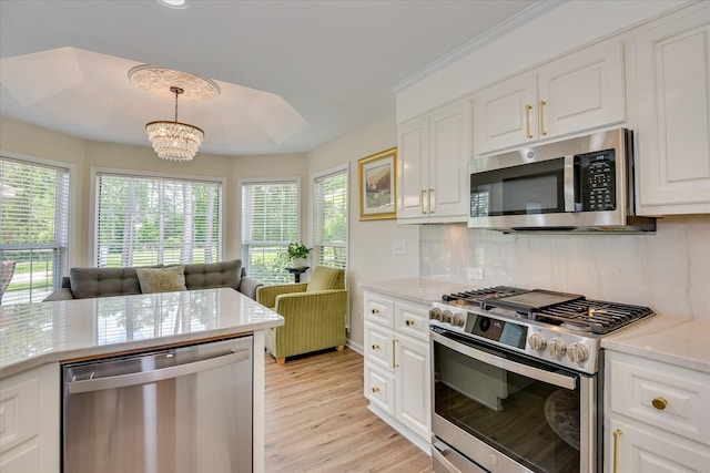 267 Fairway Dr, Mccormick, SC 29835 - kitchen with stainless steel appliances, white cabinets, light wood-style floors, a chandelier, and decorative backsplash