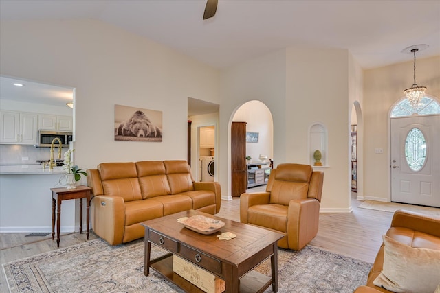 267 Fairway Dr, Mccormick, SC 29835 - living room featuring arched walkways, light wood-style floors, vaulted ceiling, baseboards, and washer / dryer