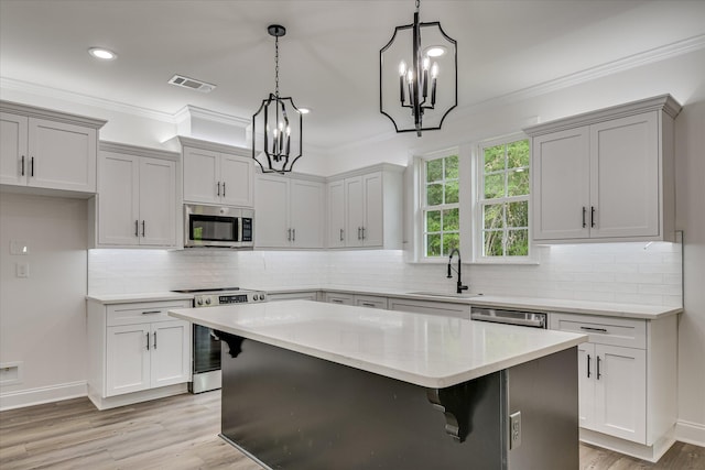 109 Dogwood Trl, Hephzibah, GA 30815 - kitchen with stainless steel appliances, a chandelier, crown molding, a center island, and light wood-style floors
