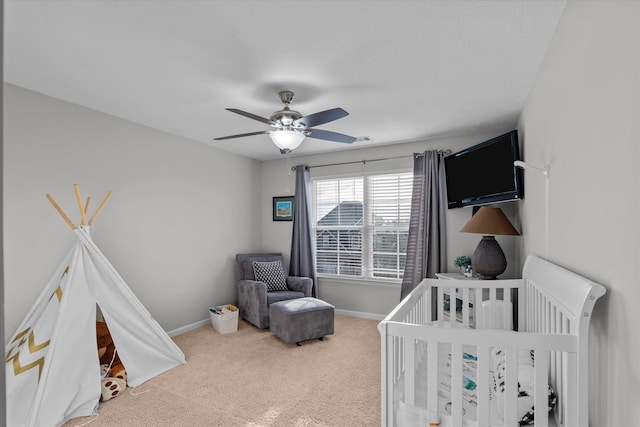 bedroom with a nursery area, carpet floors, a ceiling fan, and baseboards