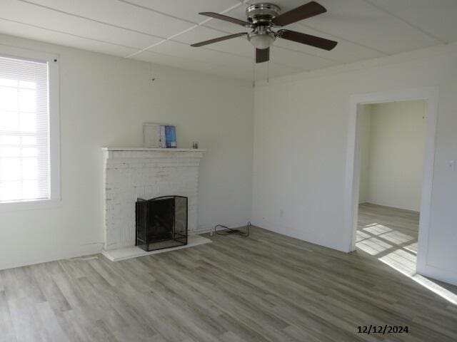 unfurnished living room featuring hardwood / wood-style floors, a brick fireplace, and ceiling fan