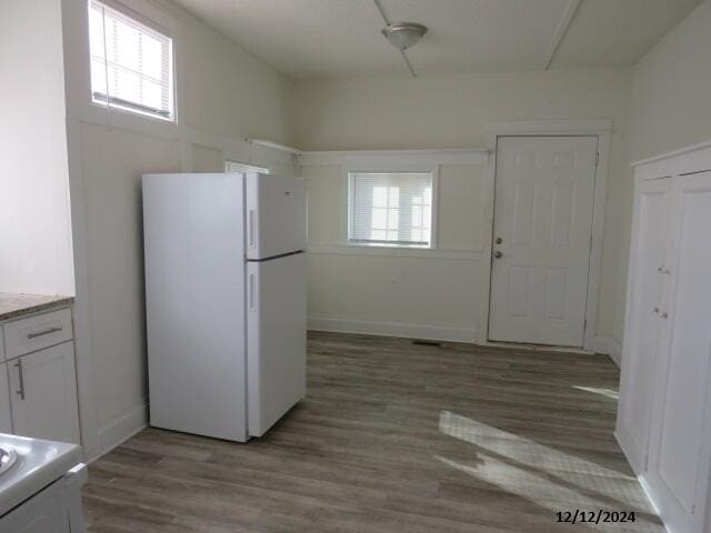 kitchen with light hardwood / wood-style floors, white fridge, and white cabinetry