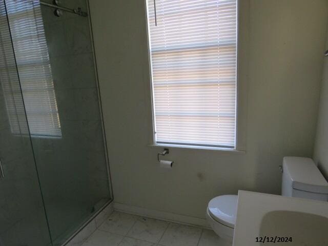 bathroom featuring toilet and a shower with shower door