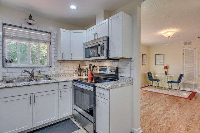 1612 Fairwood Dr, Augusta, GA 30909 - kitchen with stainless steel appliances, decorative backsplash, light wood-type flooring, white cabinetry, and recessed lighting
