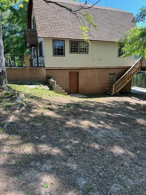 rear view of property with roof with shingles and stairway