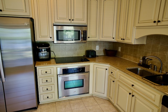 kitchen featuring sink, decorative backsplash, light tile patterned floors, appliances with stainless steel finishes, and light stone counters