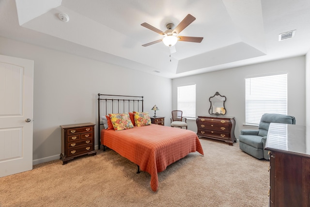 carpeted bedroom with a tray ceiling and ceiling fan