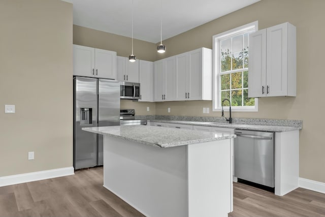 kitchen with stainless steel appliances, a kitchen island, and white cabinetry