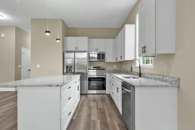 kitchen with sink, stainless steel appliances, a kitchen island, decorative light fixtures, and white cabinets