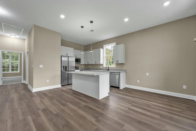 kitchen with sink, a kitchen island, decorative light fixtures, white cabinets, and appliances with stainless steel finishes