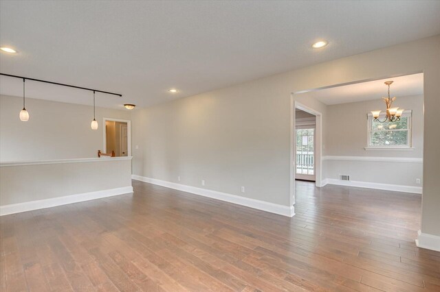 empty room with dark hardwood / wood-style floors and a notable chandelier