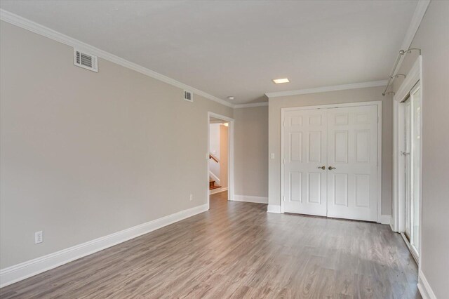 unfurnished bedroom featuring crown molding, a closet, and light hardwood / wood-style flooring