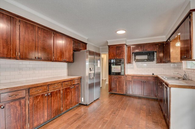 kitchen featuring backsplash, ornamental molding, sink, black appliances, and light hardwood / wood-style flooring