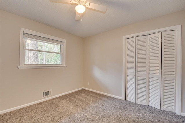 unfurnished bedroom with carpet flooring, ceiling fan, a textured ceiling, and a closet