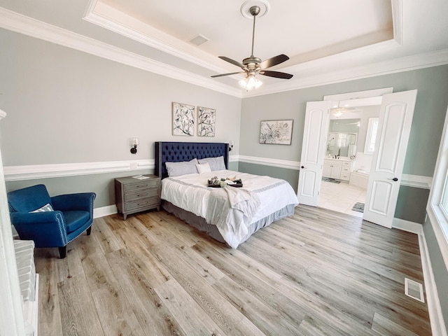 bedroom with a raised ceiling, visible vents, and light wood finished floors