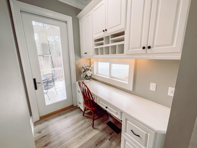 office space with plenty of natural light, built in desk, and light wood finished floors