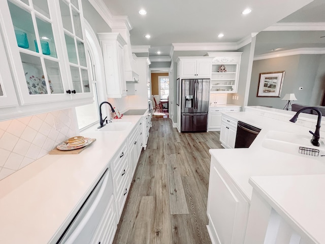 kitchen with a sink, black appliances, light countertops, and glass insert cabinets