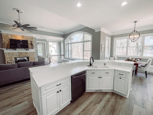 kitchen featuring white cabinets, dishwasher, open floor plan, light countertops, and a sink