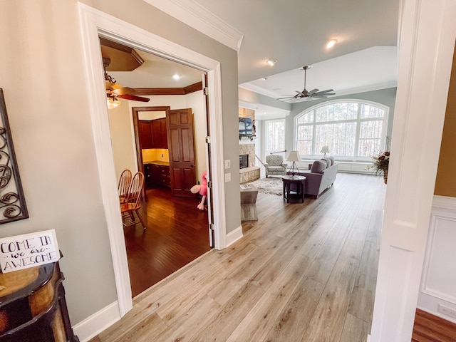 hallway with ornamental molding and light wood-style flooring