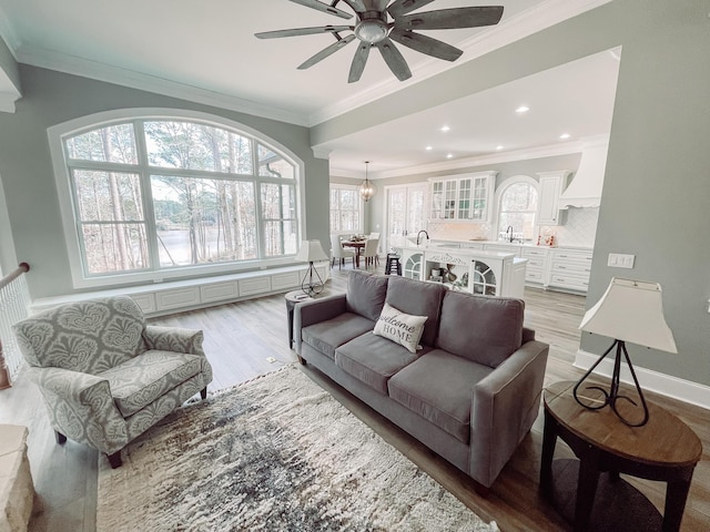 living room with ceiling fan, recessed lighting, baseboards, light wood-type flooring, and crown molding