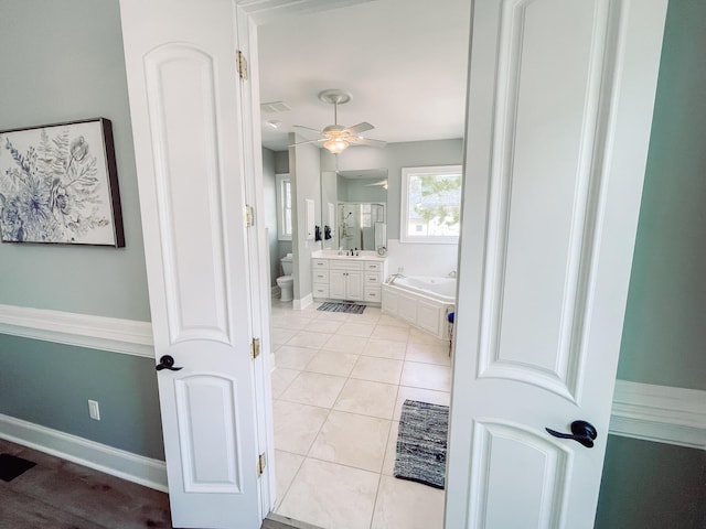 bathroom with toilet, vanity, tile patterned flooring, baseboards, and a bath