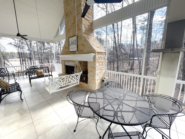 view of patio with a fireplace, a ceiling fan, and outdoor dining space