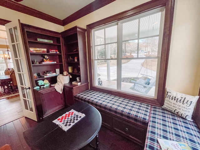 living area with an inviting chandelier, dark wood finished floors, crown molding, and french doors