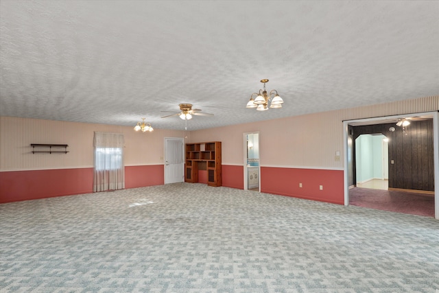 spare room featuring carpet flooring, a textured ceiling, and ceiling fan with notable chandelier