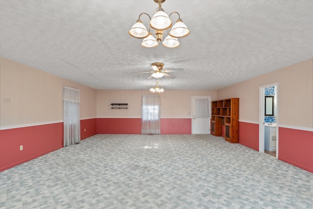 spare room with a textured ceiling, light colored carpet, and ceiling fan with notable chandelier