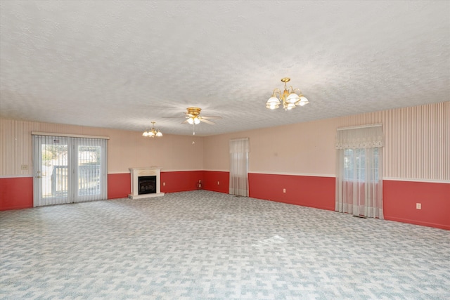 unfurnished living room with carpet flooring, a textured ceiling, and ceiling fan with notable chandelier