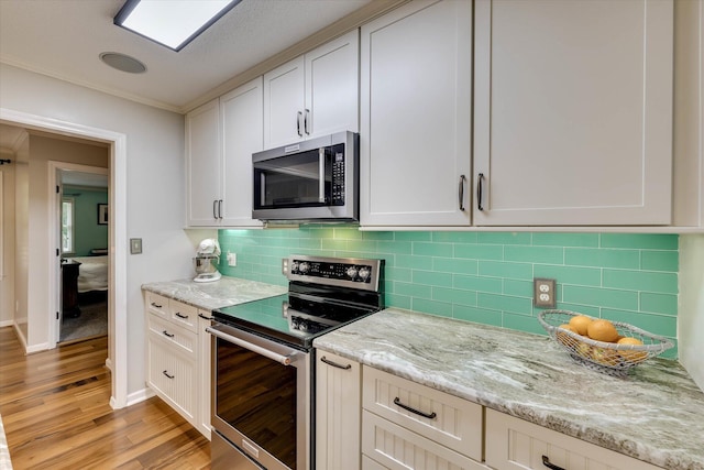 213 Oak Ln, Waynesboro, GA 30830 - kitchen with appliances with stainless steel finishes, light wood-type flooring, light stone countertops, backsplash, and ornamental molding