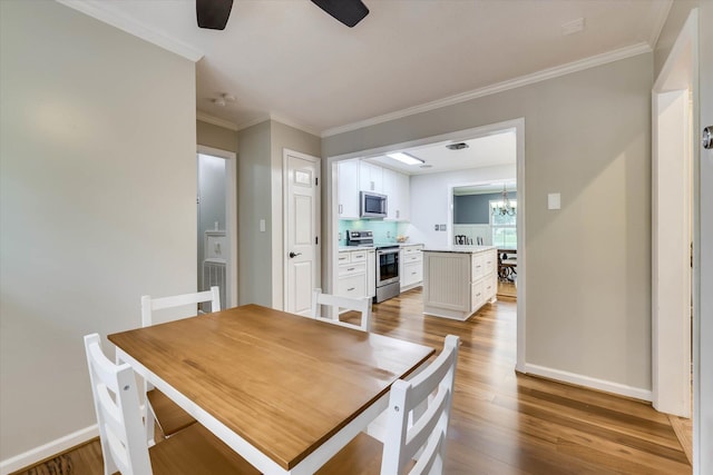 213 Oak Ln, Waynesboro, GA 30830 - dining room with ceiling fan, a chandelier, light wood finished floors, crown molding, and baseboards