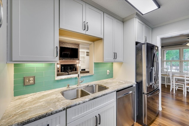 213 Oak Ln, Waynesboro, GA 30830 - kitchen featuring stainless steel appliances, a sink, backsplash, light stone countertops, and ornamental molding