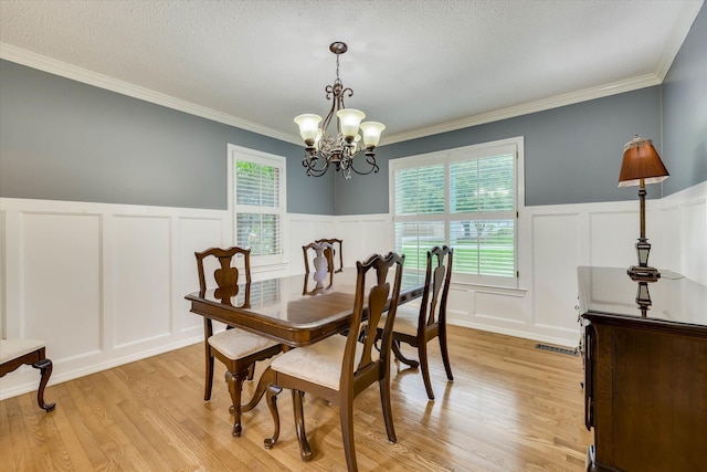 213 Oak Ln, Waynesboro, GA 30830 - dining room featuring a decorative wall, a chandelier, a wainscoted wall, light wood-style flooring, and ornamental molding