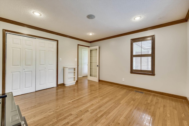 213 Oak Ln, Waynesboro, GA 30830 - unfurnished bedroom featuring a textured ceiling, baseboards, light wood-style flooring, ornamental molding, and a closet